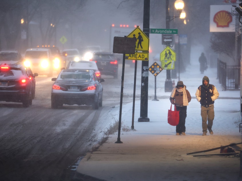 caption: Pedestrians navigate a snow-covered sidewalk in Chicago, on Thursday. Severe winter weather has impacted tens of millions of people in the U.S.