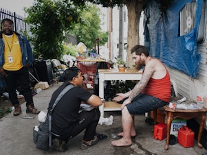 caption: Anthony Velbis, a nurse with the homeless service agency HOPICS, checks up on Anthony Boladeres outside the RV where he's living in South Los Angeles. "It's nice being able to meet the client where they're at," Velbis says.
