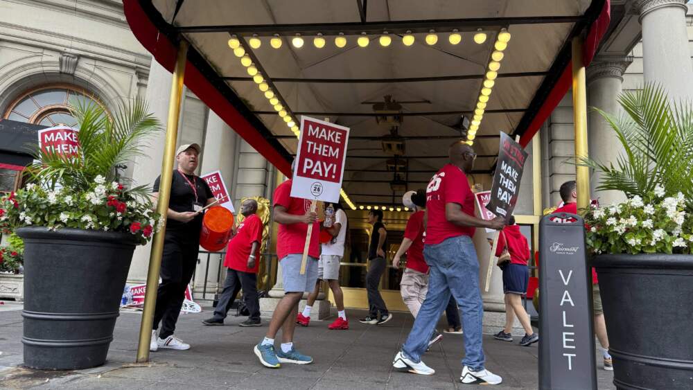 caption: Hotel workers on strike chant and beat drums while picketing outside the Fairmont Copley Plaza hotel on Sunday in Boston. (Rodrique Ngowi/AP)