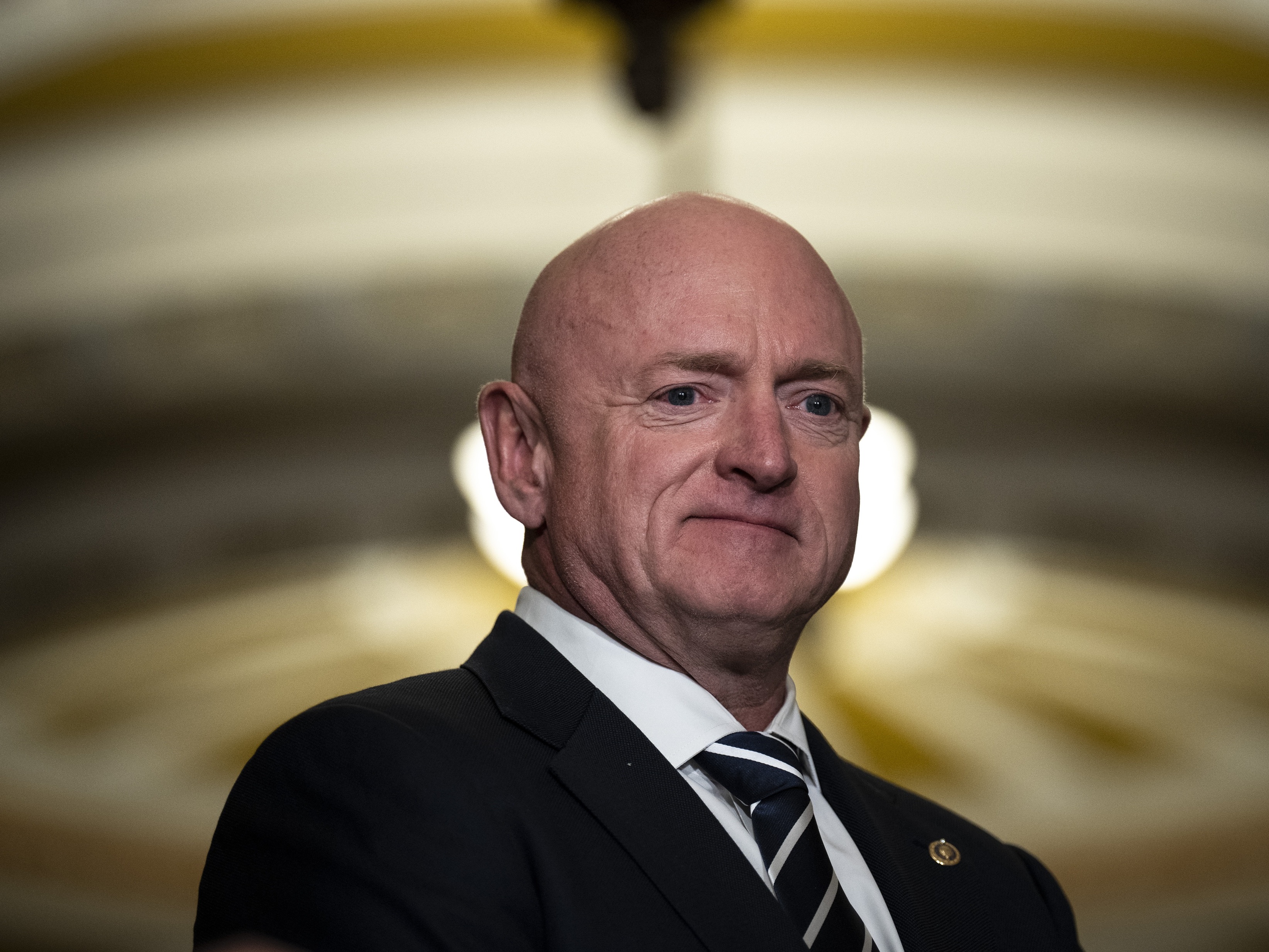 caption: Sen. Mark Kelly waits to speak during a news conference at the U.S. Capitol in 2023.