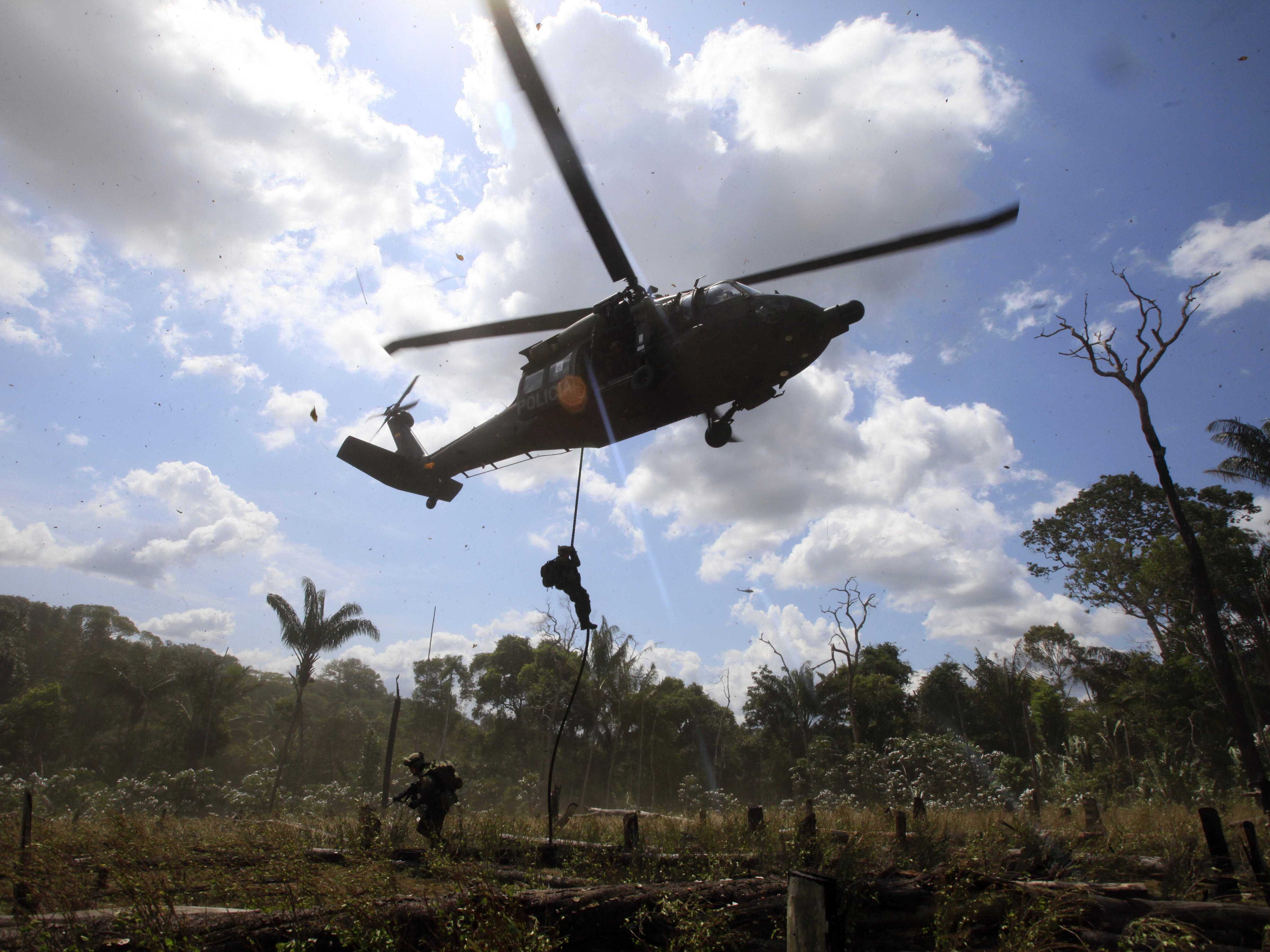 caption: Police rappel from a helicopter to destroy a cocaine processing lab in Puerto Concordia in Colombia's southern Meta state.
