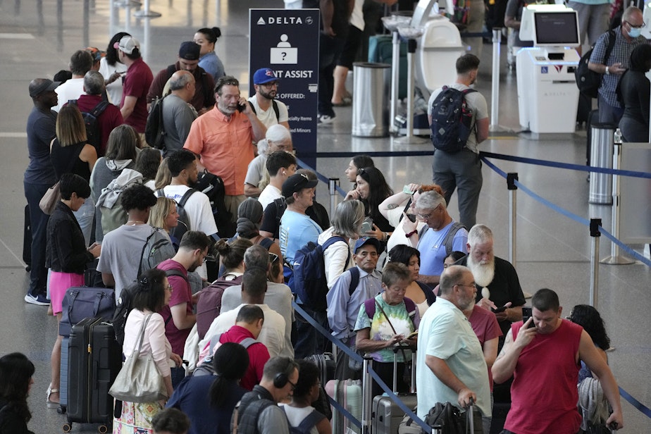 caption: Passengers wait in line for assistance at the Delta Terminal, Friday, July 19, 2024, at Logan International Airport in Boston.