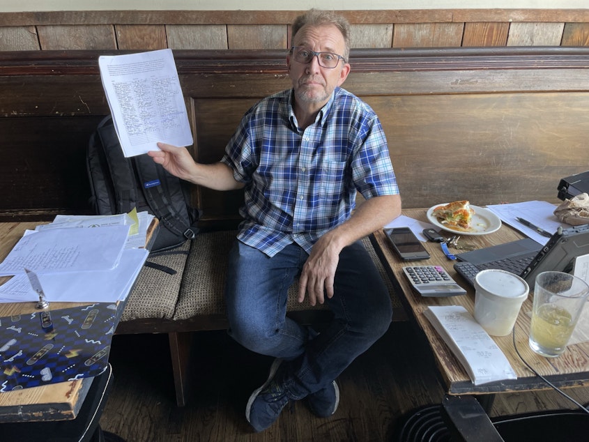 caption: Christopher Forczyk owns Smith, a bar on 15th Avenue. He holds up a petition of business owners he says oppose the proposed Business Improvement Area