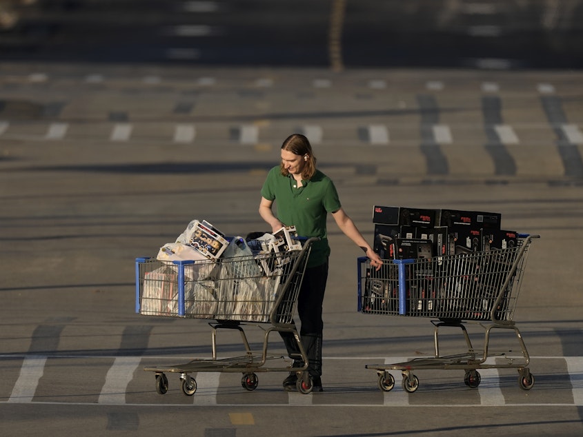 caption: A shopper pushes two carts during last year's Black Friday sale at a Best Buy store in Overland Park, Kan.