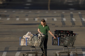 caption: A shopper pushes two carts during last year's Black Friday sale at a Best Buy store in Overland Park, Kan.