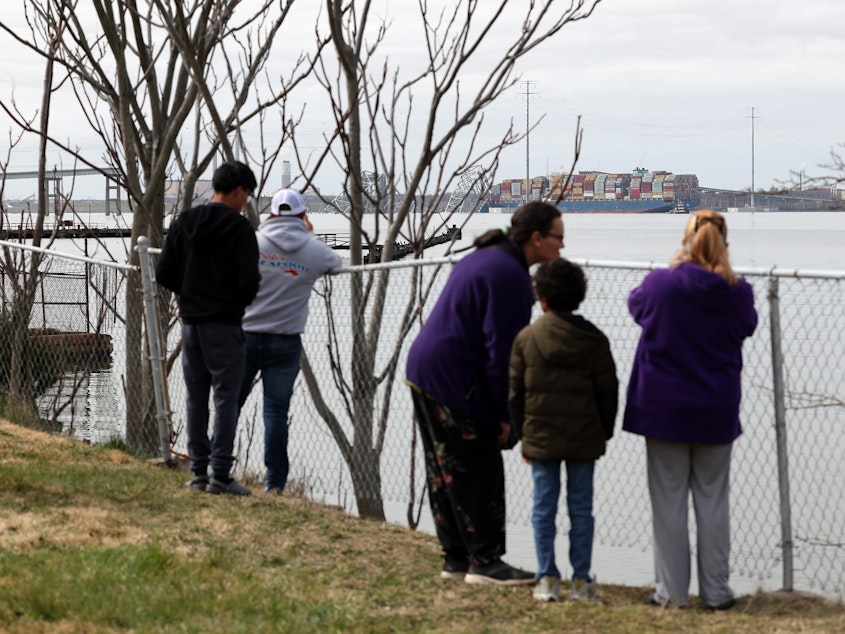 caption: Residents look on after a cargo ship ran into and collapsed the Francis Scott Key Bridge on March 26, 2024 in Baltimore. Conspiracy theorists online quickly spread narratives to millions online that the accident was part of a nefarious scheme.