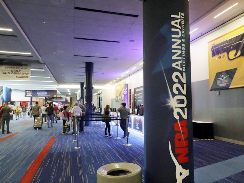caption: Attendees of the NRA's annual convention gather by booths in the exhibit halls of the George R. Brown Convention Center in Houston on Thursday.
