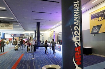 caption: Attendees of the NRA's annual convention gather by booths in the exhibit halls of the George R. Brown Convention Center in Houston on Thursday.