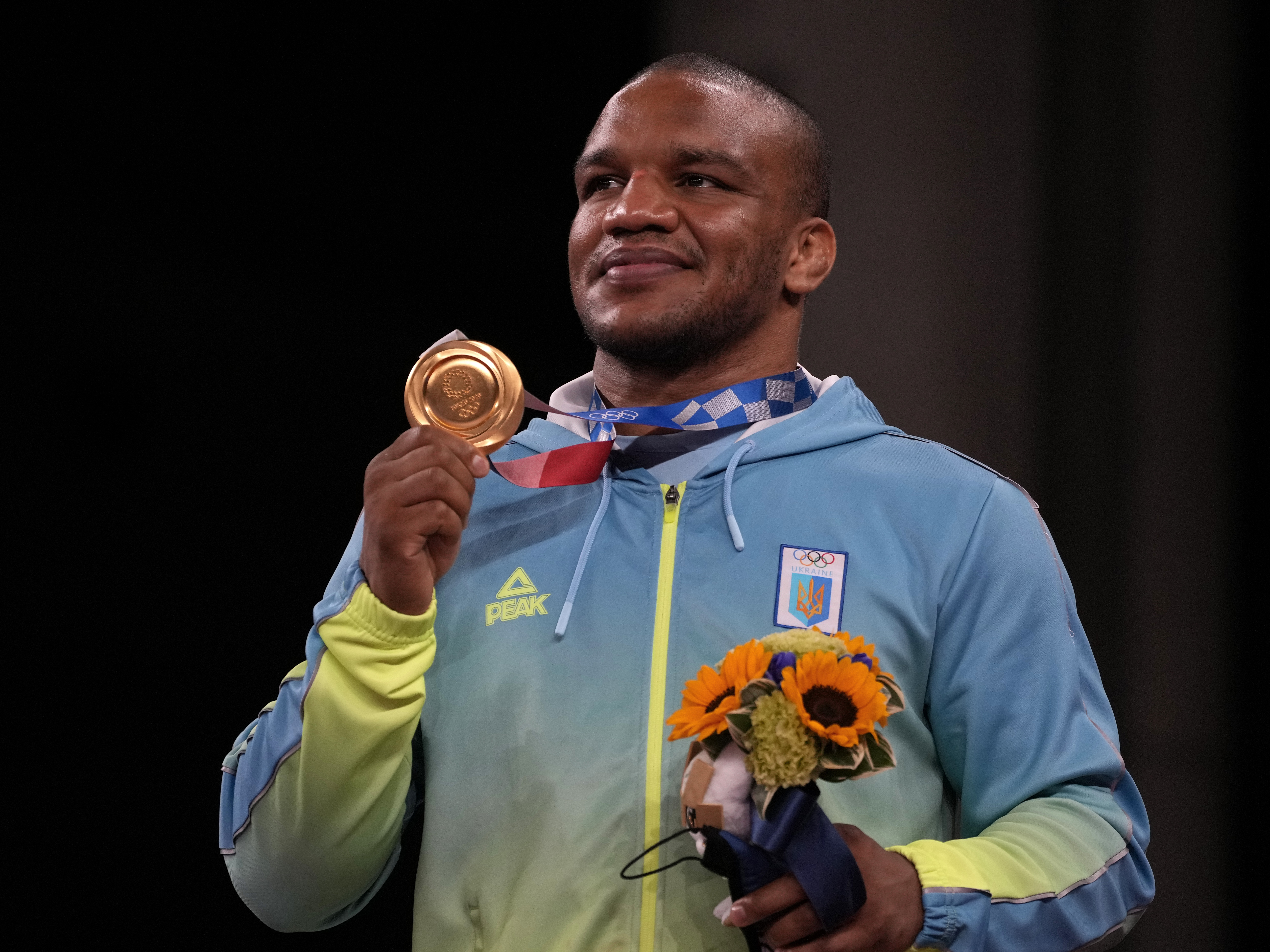 caption: Gold medalist Zhan Beleniuk of Ukraine celebrates on the podium during the medal ceremony for men's 87-kilogram Greco-Roman wrestling.