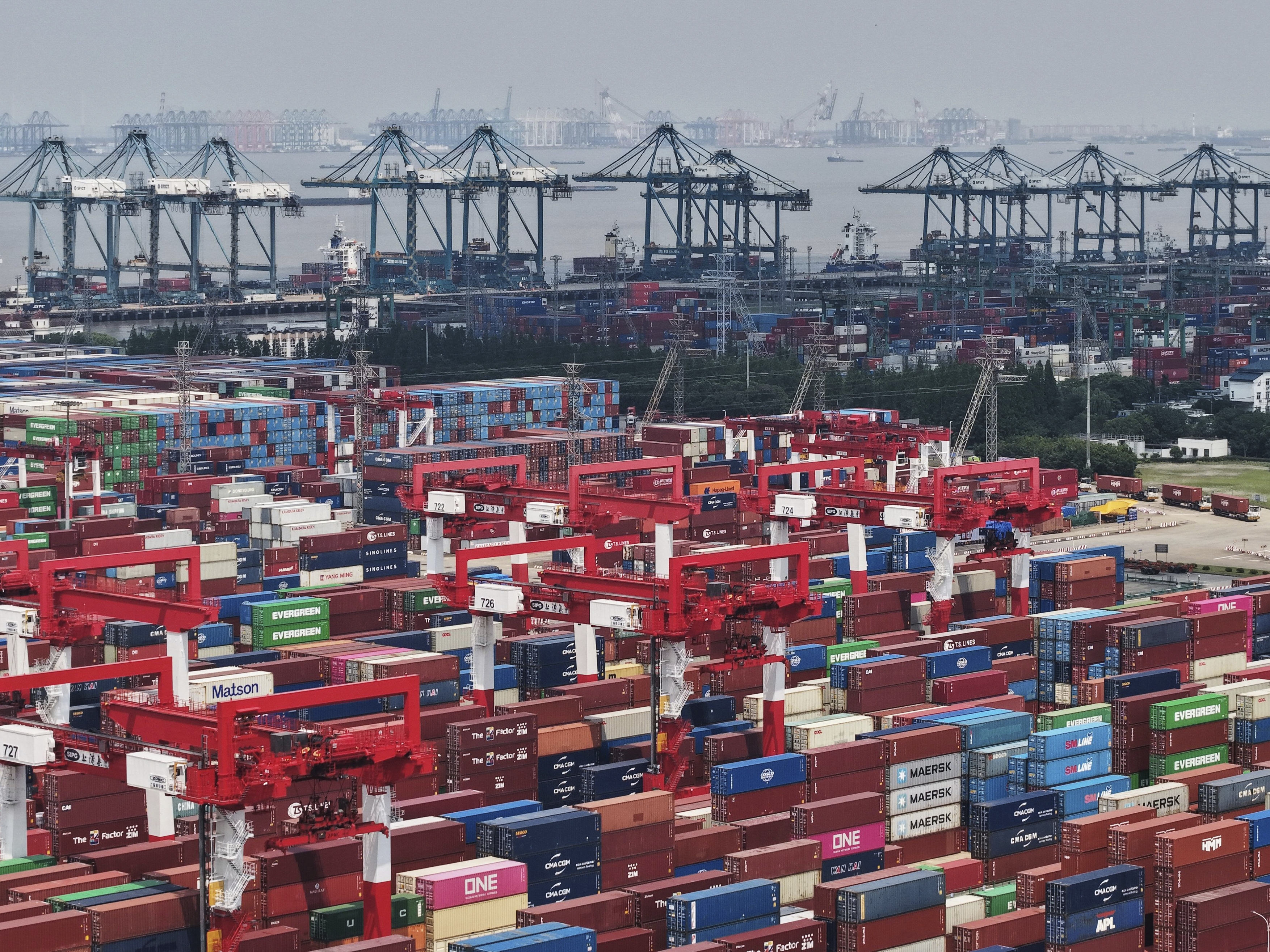 caption: Trucks loaded with containers move through a port in Shanghai, China Monday, June 9, 2025.
