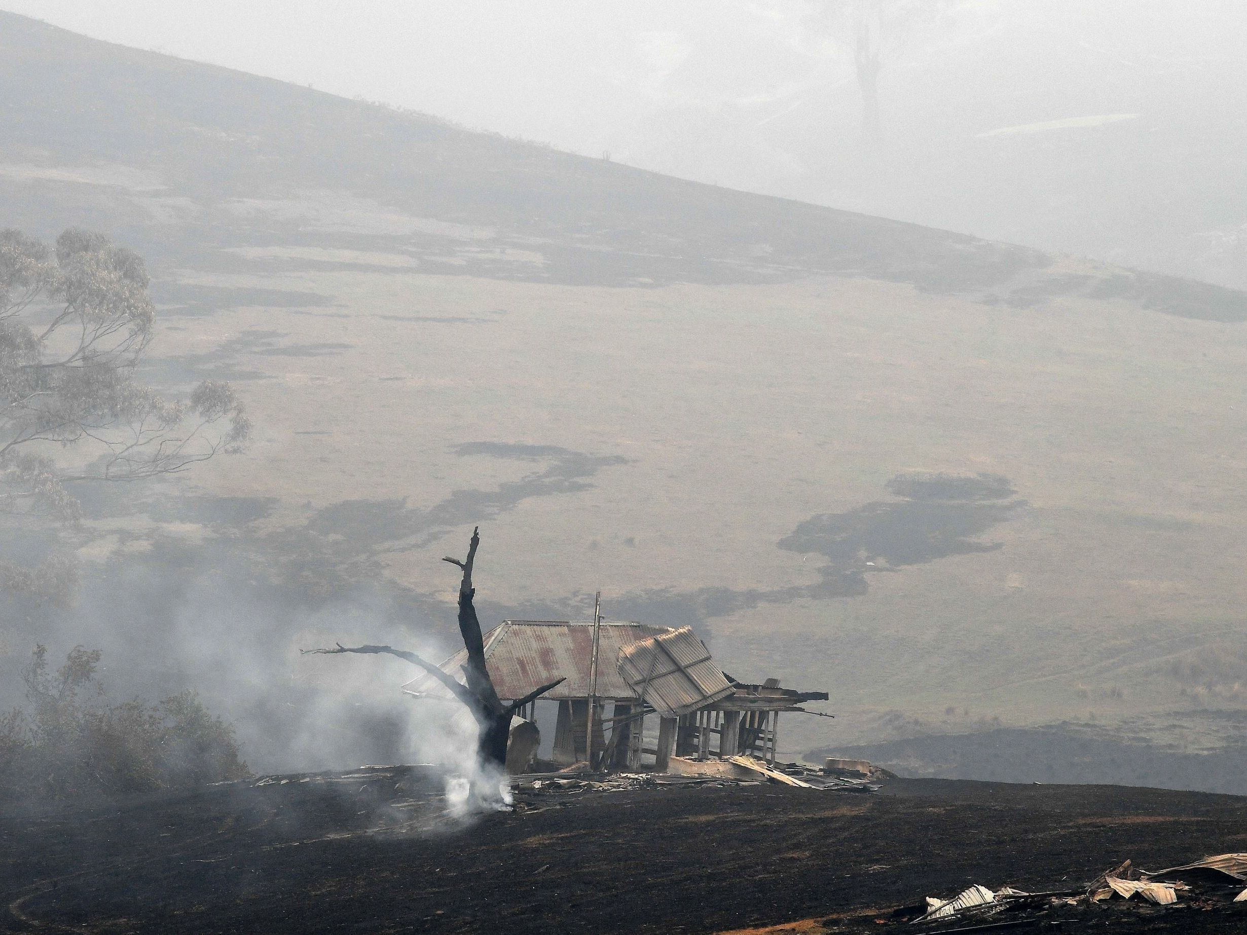 caption: Smoke rises from a tree next to a fire-ravaged house in Australia's New South Wales on Monday. Reserve troops were deployed to parts of three Australian states after fires worsened over the weekend.