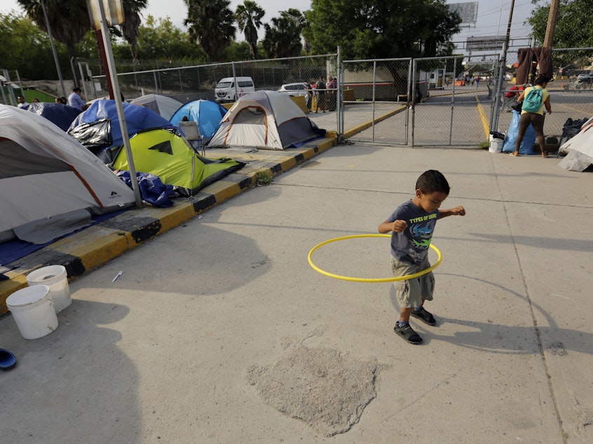 caption: William Linares, a 5-year-old from Honduras, plays in an encampment where he is living near the international bridge in Matamoros, Mexico, on April 30. The boy is traveling with his mother, Suanny Gomez, and seeking asylum in the United States.