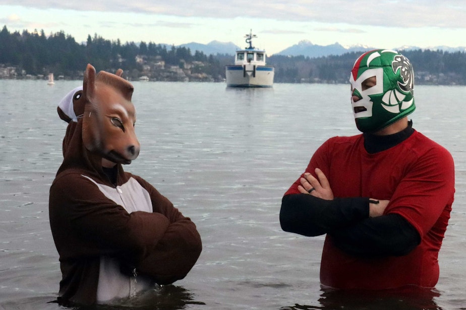 caption: Mike Rigler dresses as a Mexican wrestler with Chloe Rigler who is wearing a horse mask as they enjoy the Polar Plunge Monday at Matthews Beach Park in Seattle.