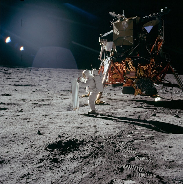 caption: Astronaut Buzz Aldrin deploys a solar wind collector, a foil sheet pointing at the sun, on the moon during the Apollo 11 mission in July 1969.
