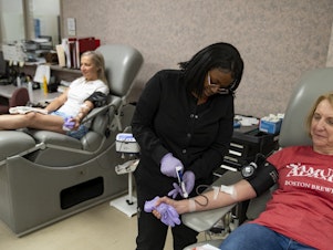 caption: Tuyishimire Primitiva, phlebotomist with the American Red Cross, draws whole blood from Teresa McLeland at the American Red Cross on April 12, 2023 in Louisville, Kentucky.