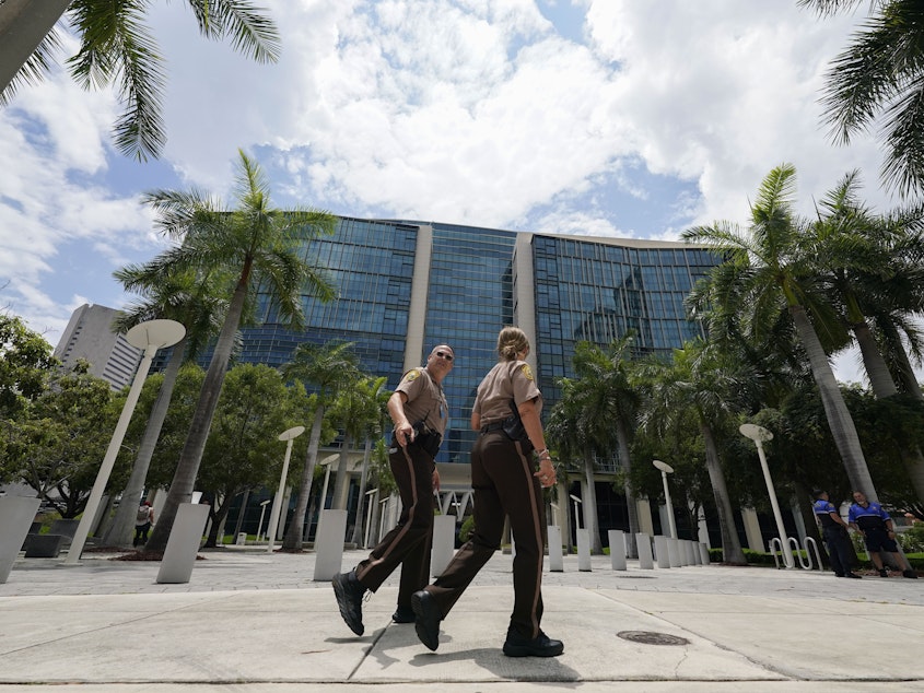 caption: Miami-Dade Sheriff deputies walk in front of the Wilkie D. Ferguson Jr. federal courthouse building in Miami on Friday.