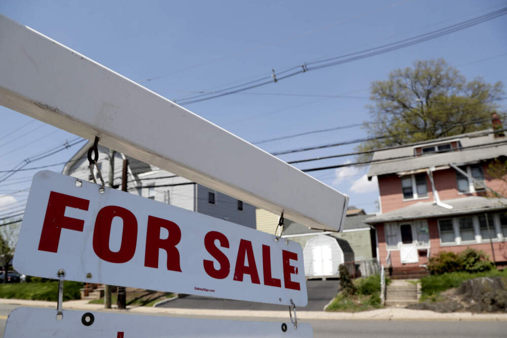 caption: A for sale sign hangs from a post outside of a vacant building. (Julio Cortez/AP)