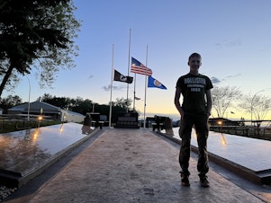 caption: Dominique Claseman stands in front of the memorial he built for his Eagle Scouts project.