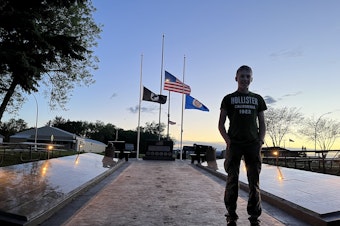 caption: Dominique Claseman stands in front of the memorial he built for his Eagle Scouts project.