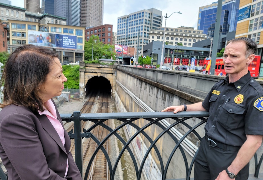 caption: Washington Senator Maria Cantwell and Seattle Fire Battalion Chief Andy Collins inspect the rain tunnel entrance in Pioneer Square on Monday, May 22, 2023.