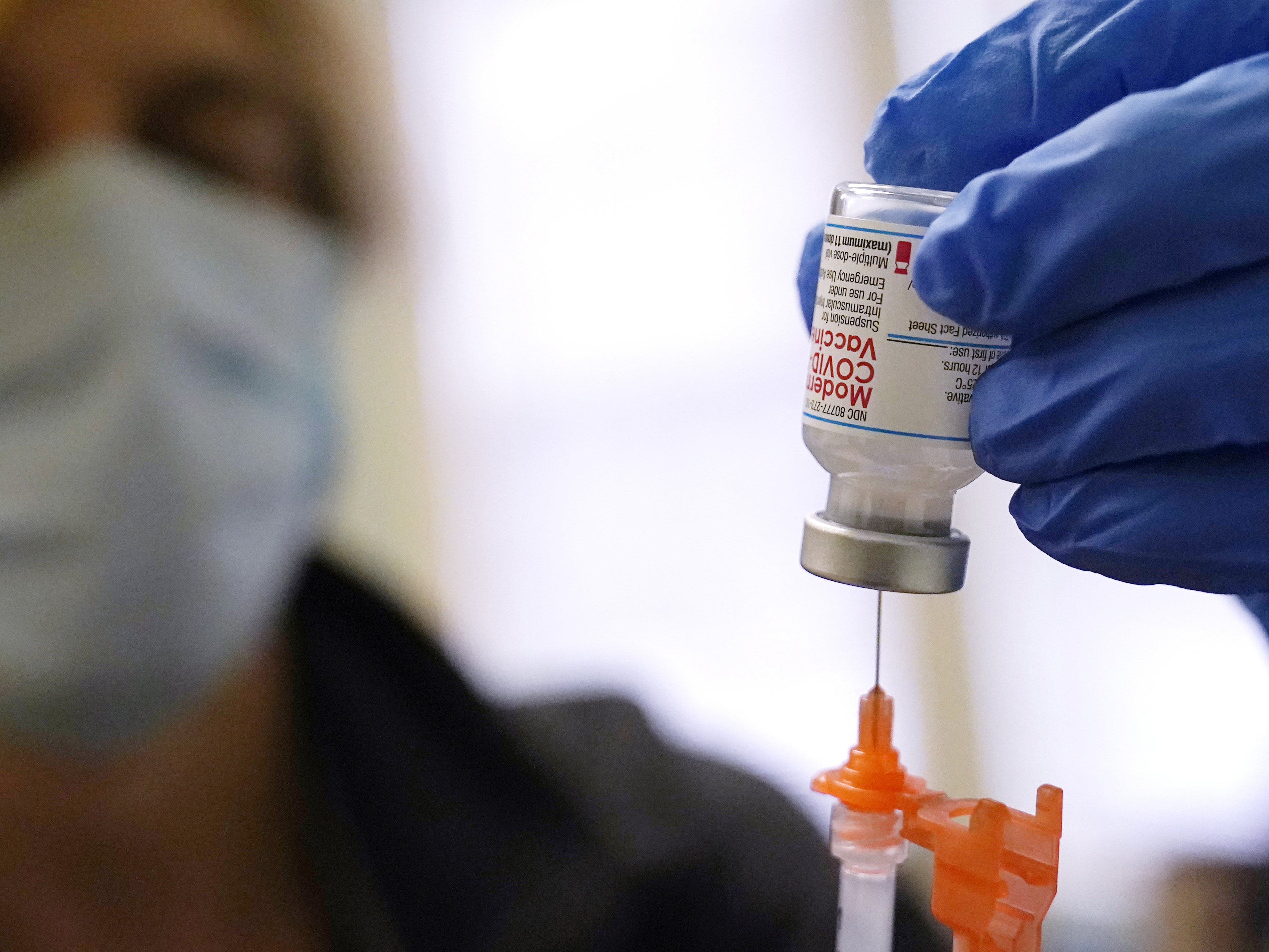 caption: A booster dose of the Moderna COVID-19 vaccine is prepared during a vaccination clinic on Dec. 29 in Lawrence, Mass. The FDA is now shortening the wait time between the second dose and the booster to five months from six months.
