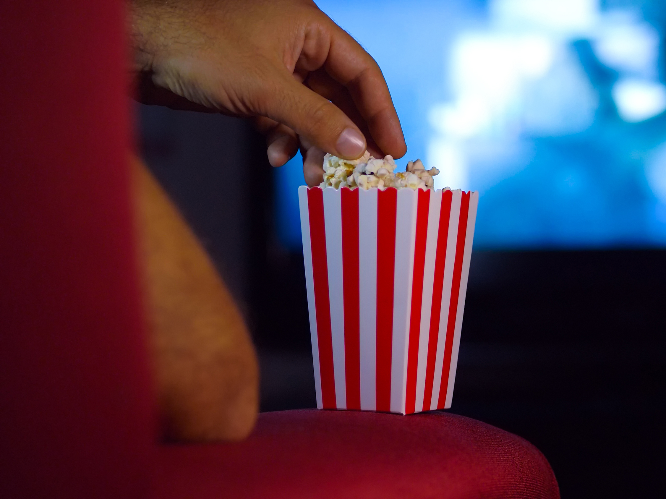 Eating popcorn while watching a movie on the couch.