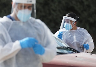 caption: Frontline healthcare workers work at a drive-in COVID-19 testing site amid a surge of COVID-19 cases in El Paso on November 13, 2020. (Mario Tama/Getty Images)