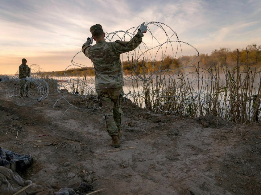 caption: Texas National Guard soldiers install additional razor wire lie along the Rio Grande on Jan. 10 in Eagle Pass, Texas.