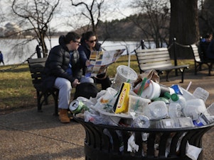 caption: A trash can overflows as people sit outside of the Martin Luther King Jr. Memorial in Washington, D.C.