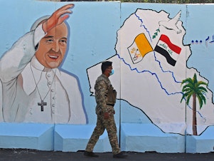 caption: An Iraqi policeman walks by a mural depicting Pope Francis on the outer walls of Our Lady of Salvation Church in Baghdad on Monday. Pope Francis' visit from March 5 to 8 will include trips to Baghdad, the city of Mosul and a meeting with the country's top Shiite cleric Grand Ayatollah Ali al-Sistani.