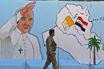 caption: An Iraqi policeman walks by a mural depicting Pope Francis on the outer walls of Our Lady of Salvation Church in Baghdad on Monday. Pope Francis' visit from March 5 to 8 will include trips to Baghdad, the city of Mosul and a meeting with the country's top Shiite cleric Grand Ayatollah Ali al-Sistani.