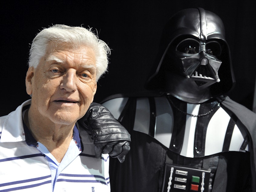 caption: British actor David Prowse, who played Darth Vader in the first Star Wars trilogy, poses with a fan dressed in a Darth Vader costume during a Star Wars convention on April 27, 2013. On Sunday morning, Prowse's management company shared the news of his death at age 85.