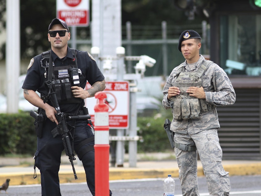 caption: Security guards outside the main gate at Hawaii's Joint Base Pearl Harbor-Hickam following the shooting. The Navy says the gunman was assigned to a nuclear-powered attack submarine currently in port.