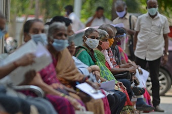 caption: People wait their turn to receive the COVID-19 vaccine at a government hospital in Chennai, India, in April. India is among the nations which will receive surplus U.S. vaccine through the international distribution system COVAX, the White House announced.