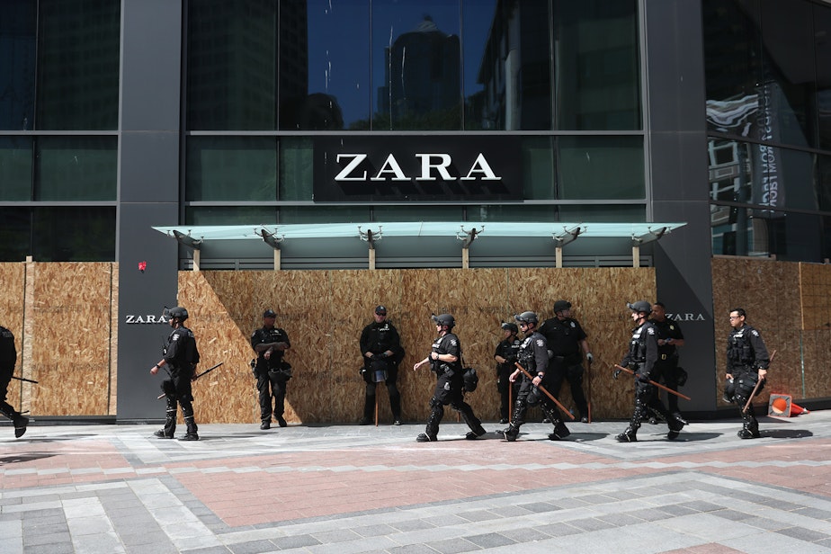 caption: Police officers walk in front of Zara's ahead of a peaceful protest march on Monday, June 1, 2020, beginning at Westlake Park in Seattle. 