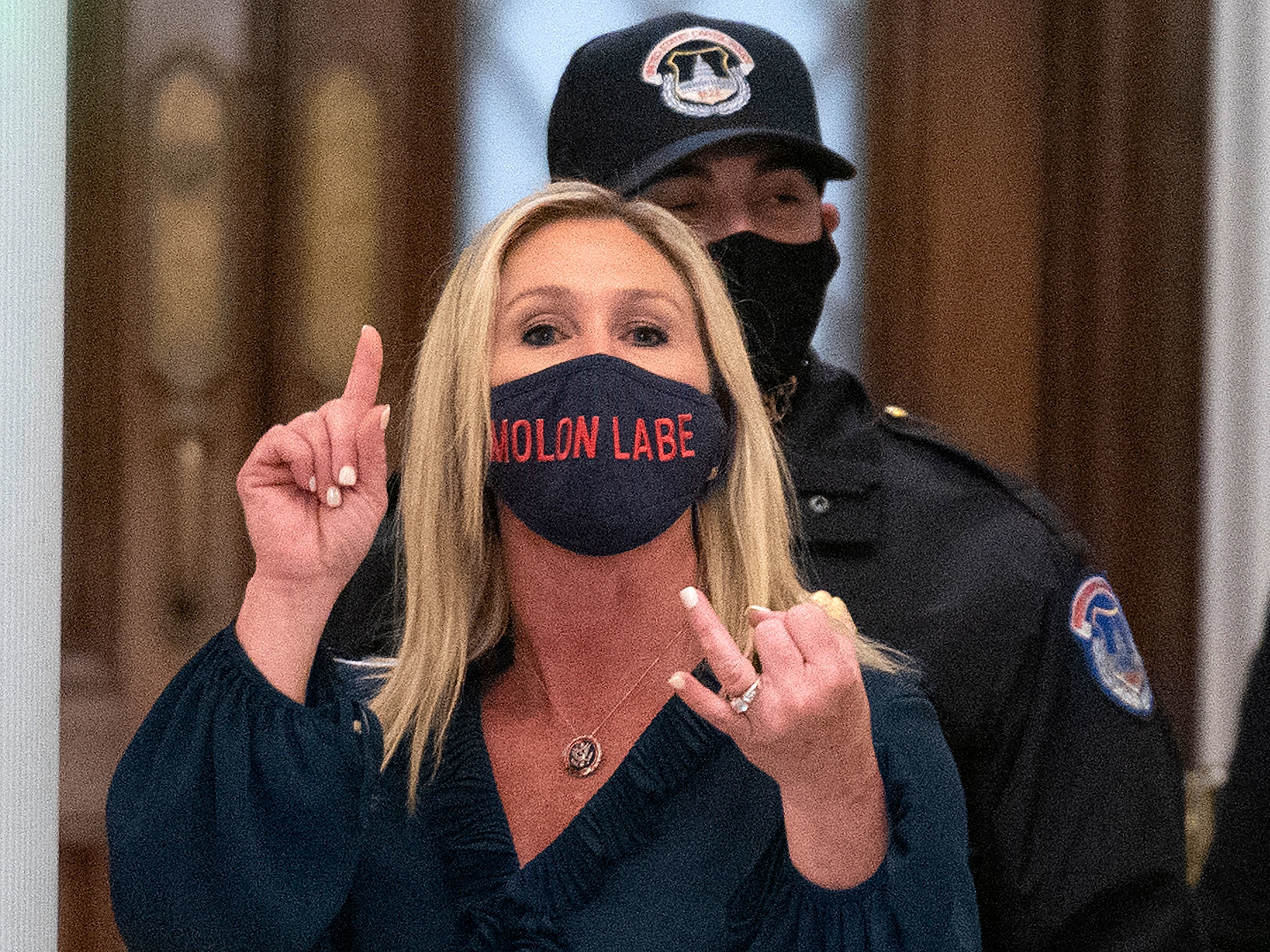 caption: Rep. Marjorie Taylor Greene, R-Ga., shouts at journalists as she goes through security outside the House chamber last month.