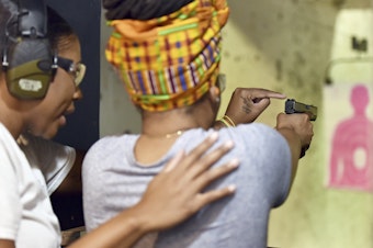 caption: Marchelle Tigner, a firearms instructor, teaches a student how to shoot a gun during a 2017 class in Lawrenceville, Ga. Tigner's goal is to train 1 million women how to shoot a gun in her lifetime. She is among the nation's Black women gun owners who say they are picking up firearms for self-protection.