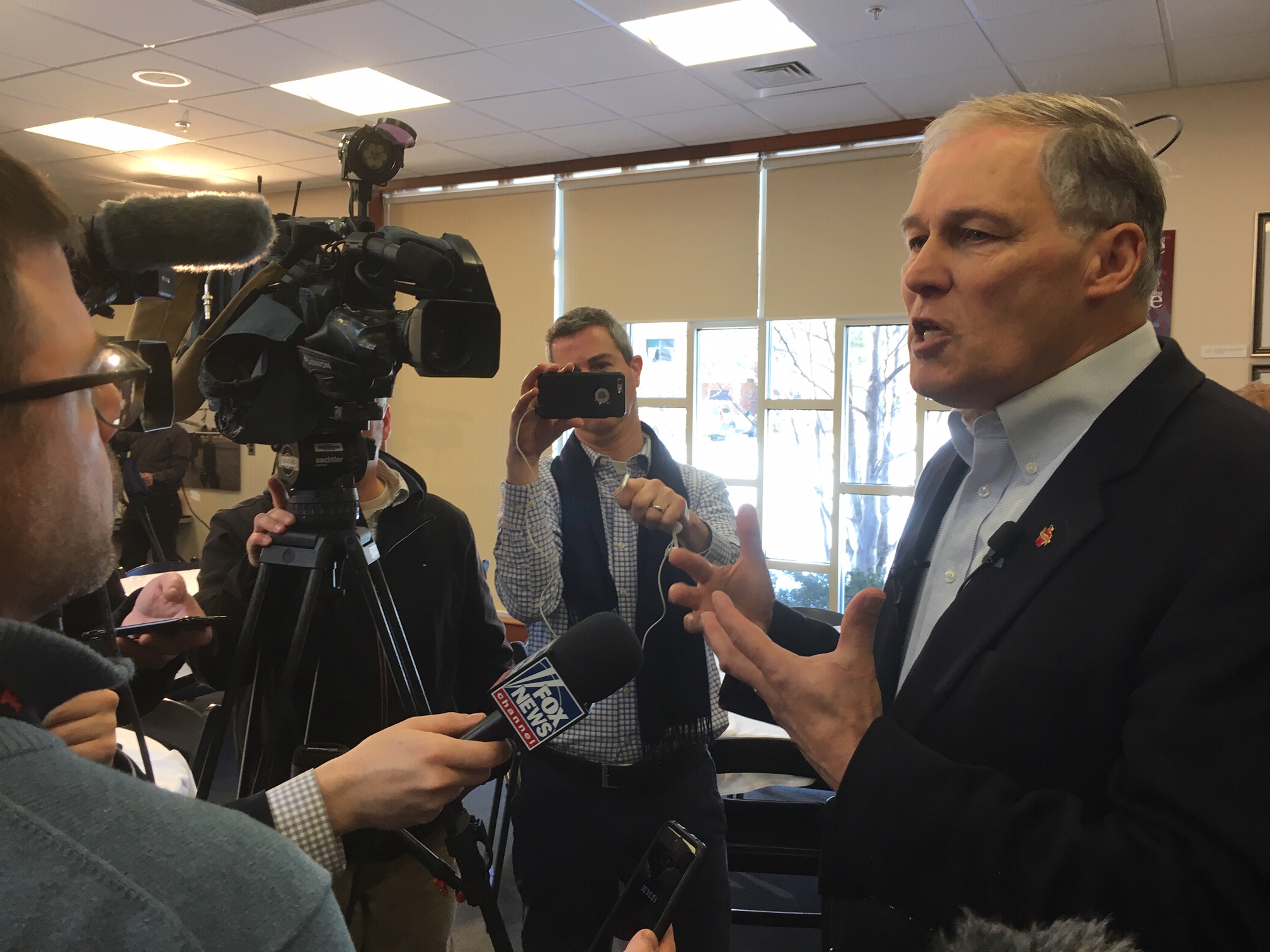 caption: Gov. Jay Inslee speaks with reporters following a talk on climate change at the New Hampshire Institute of Politics in Manchester.