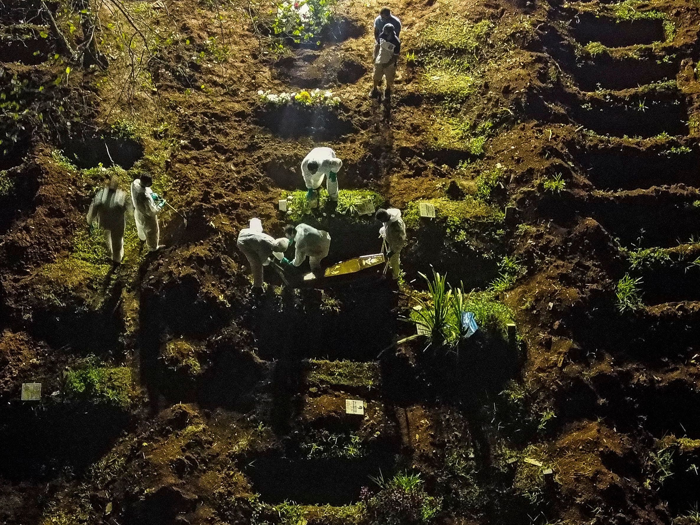 caption: An aerial view showing a coffin being buried at the Vila Formosa cemetery in Sao Paulo, Brazil, late last month. Brazil has been experiencing record numbers of coronavirus infections and COVID-19 deaths in recent weeks.
