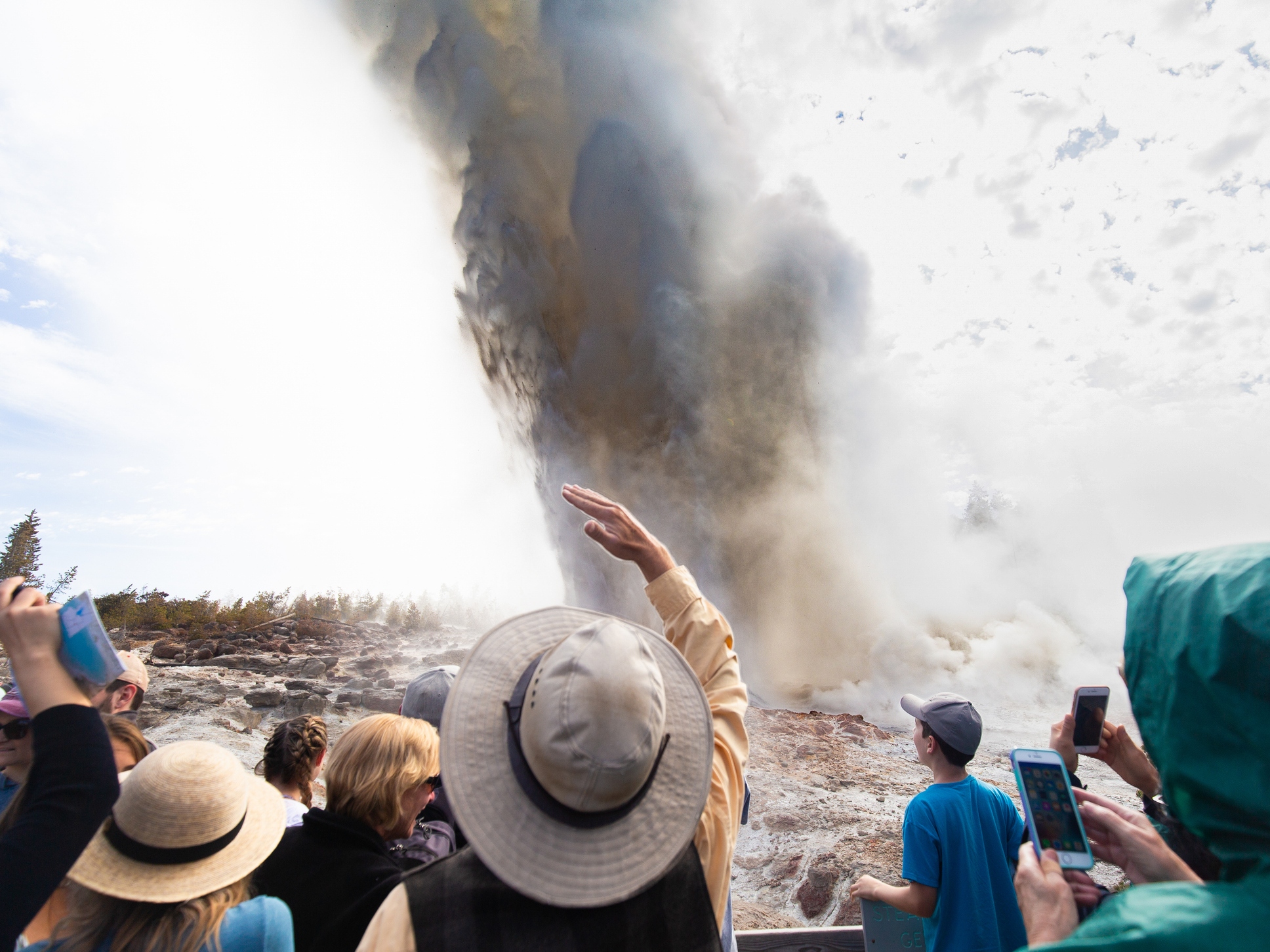 caption: Wyoming, USA - A crowd of people witness the rare eruption of Steamboat Geyser, the largest active geyser in the world.