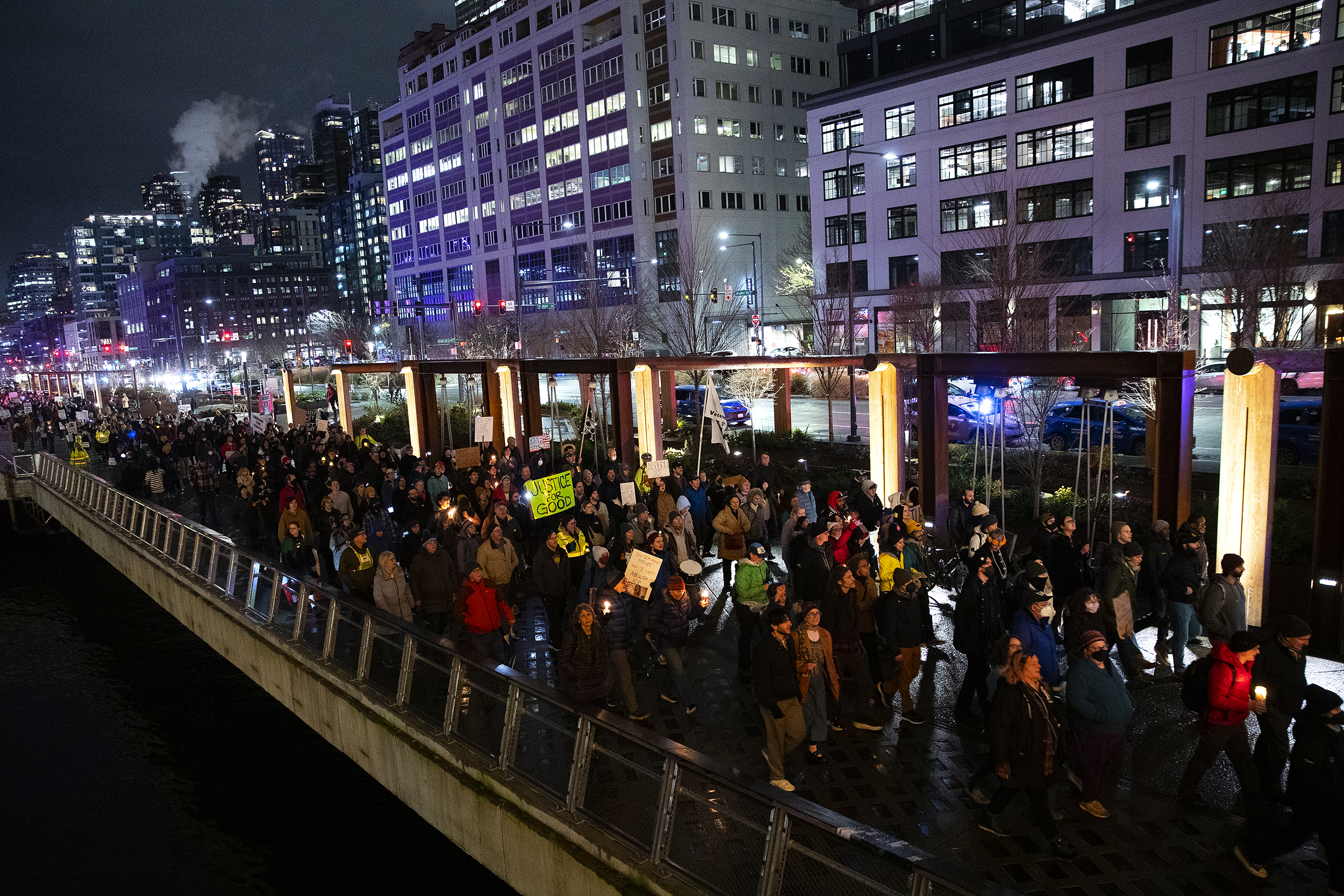 caption: Hundreds march along the waterfront following a vigil honoring Renee Nicole Good on Thursday, January 8, 2026, at Pier 58 in Seattle. 