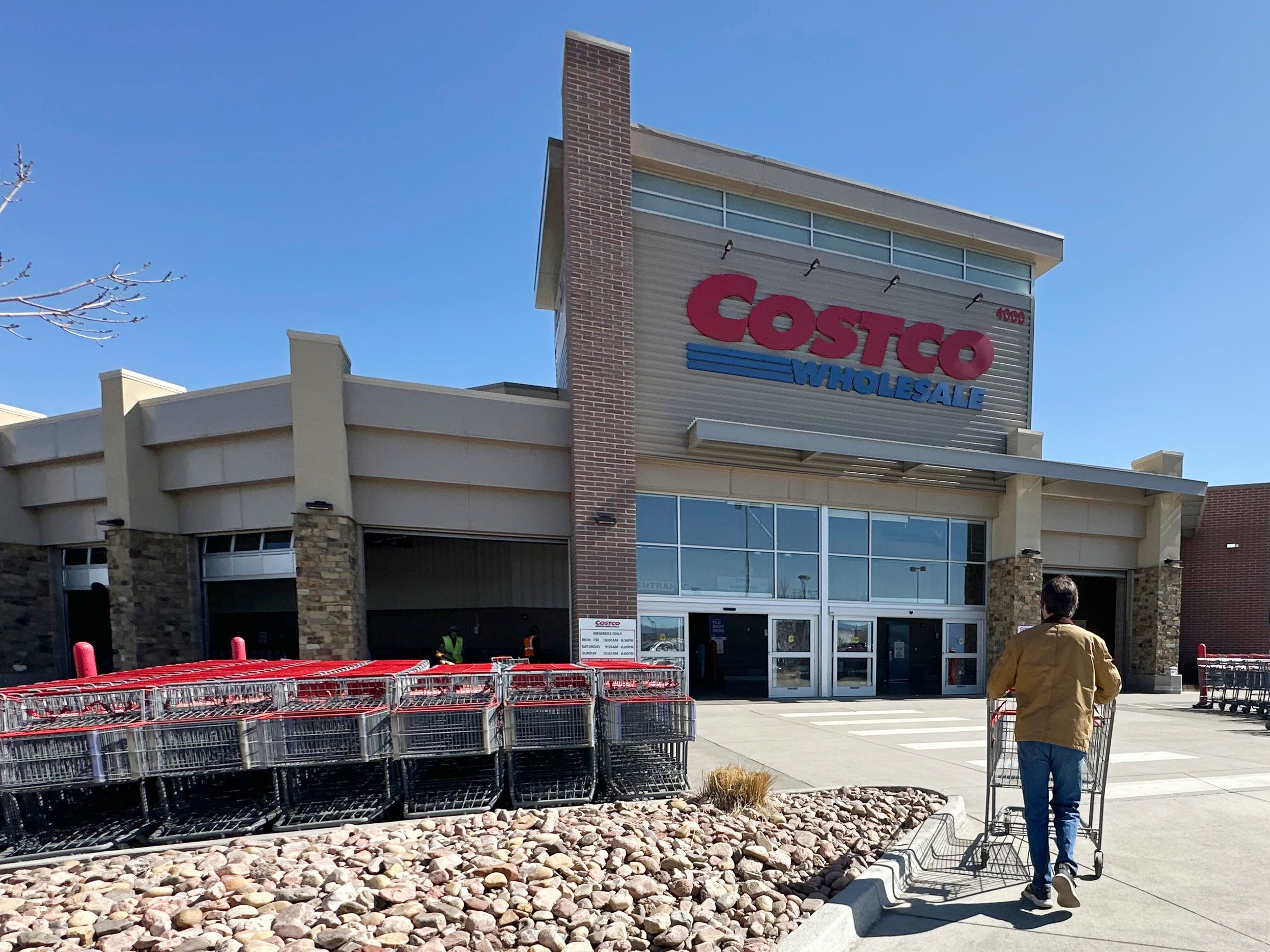 caption: A shopper pushes a cart toward the entrance of a Costco warehouse in Colorado.