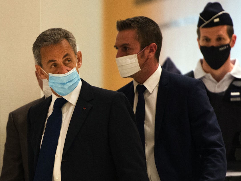 caption: French former President Nicolas Sarkozy (left) arrives to hear the verdict in a corruption trial at Porte de Clichy court house in Paris on Monday.