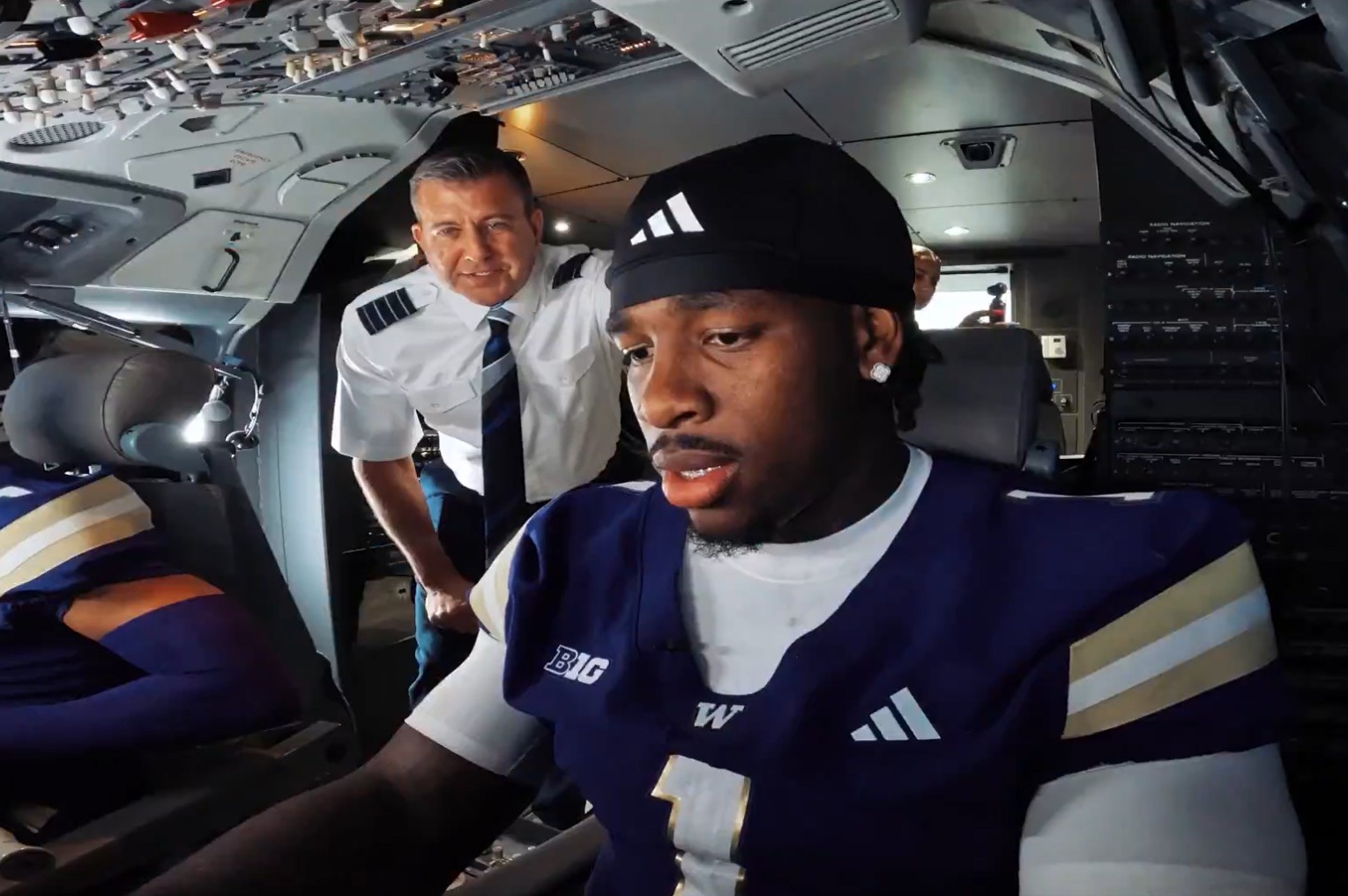 caption: University of Washington football player Jonah Coleman appears to fly a plane (or at least a flight simulator) in a recent Alaska Airlines ad.