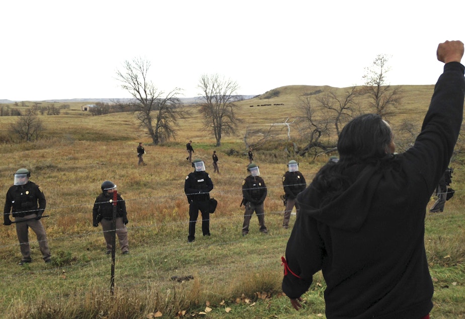 caption: A Dakota Access pipeline protester defies law enforcement officers who are trying to force them from a camp on private land in the path of pipeline construction, Thursday, Oct. 27, 2016 near Cannon Ball, N.D.