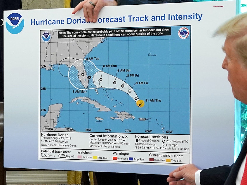 caption: In the Oval Office, President Trump references a map showing Hurricane Dorian's path. The map appears to have been altered by a black marker to extend the hurricane's range to Alabama.
