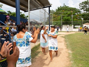 caption: Sitlali Yovana Poot Dzib, 20 (left), captain of The Amazonas of Yaxunah, high fives her teammates after a home run in a game played on Sept. 10. The indigenous women on the team live in the small Maya community of Yaxunah in Mexico's Yucatán Peninsula. They wear traditional Maya garb when they play — and eschew shoes.