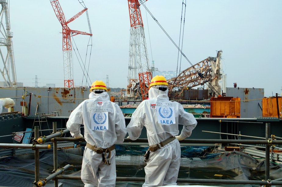 caption: Two IAEA experts examine recovery work on top of the Fukushima Daiichi Nuclear Power Station in April 2013.