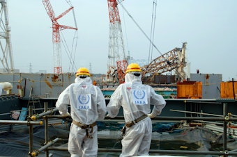 caption: Two IAEA experts examine recovery work on top of the Fukushima Daiichi Nuclear Power Station in April 2013.