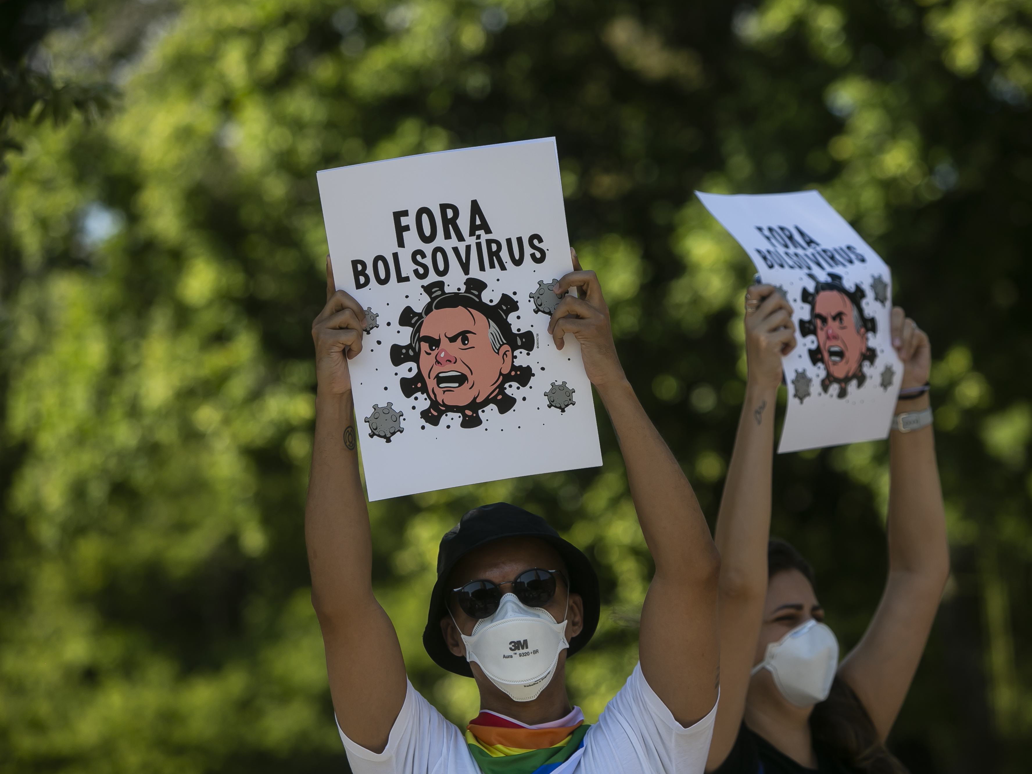 caption: Demonstrators wearing protective face masks hold signs depicting President Jair Bolsonaro as a virus protest against the government's response in combating COVID-19, demanding the impeachment of Bolsonaro, in Rio de Janeiro, Brazil, Saturday, May 29, 2021.